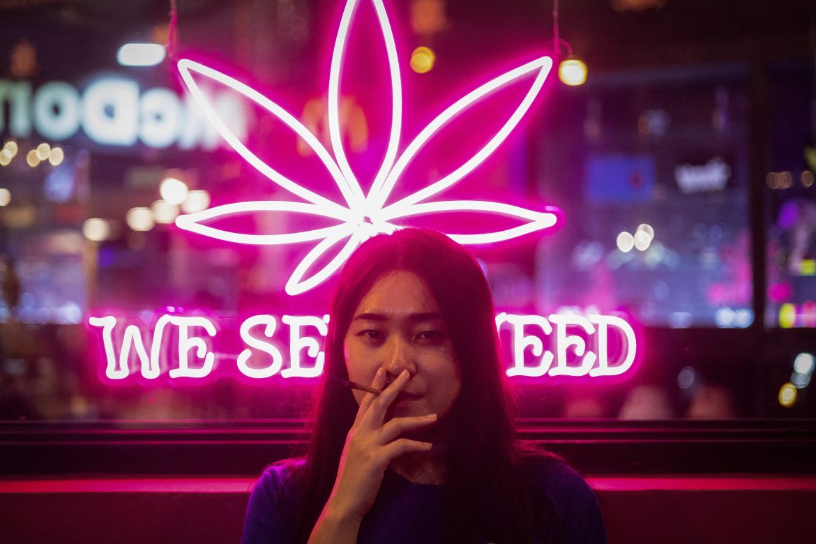 Pim smokes a joint outside the cannabis shop where she works, in Bangkok, Thailand, August 19