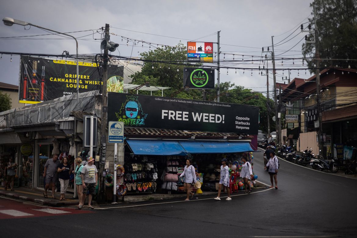 People walk in front of cannabis-related advertising signs, in Phuket, Thailand, August 12