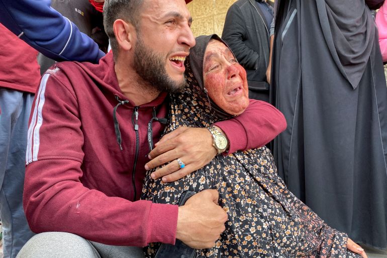 The mother of Palestinian Khalil Abu Shamala, who was killed in an Israeli strike, mourns with her face stained with his blood as Khalil's brother reacts