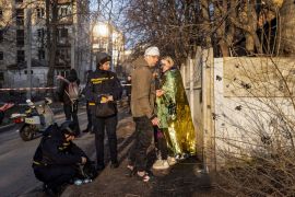 Wounded local residents stand at the site where buildings were damaged by a Russian military strike in Kharkiv on March 27, 2024 [Yevhen Titov/Reuters]