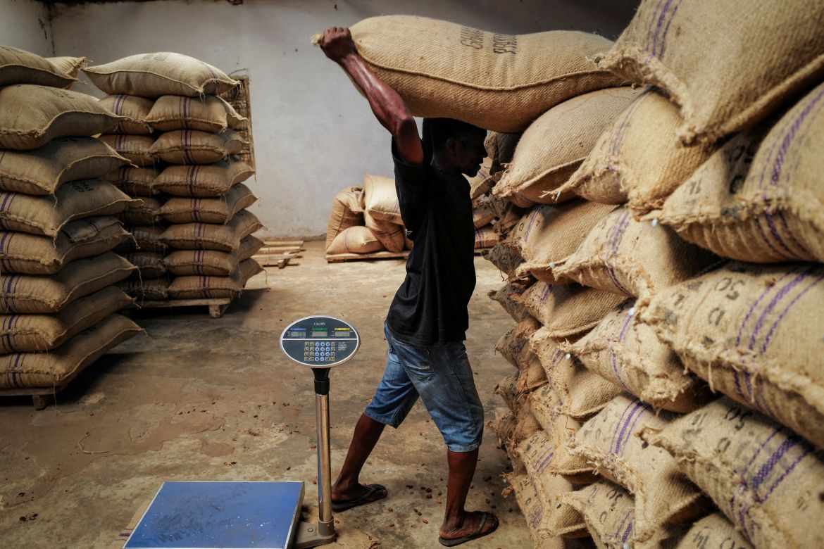 A worker transports a bag of sun-dried cocoa beans at a warehouse in Kwabeng in the Eastern Region, Ghana, February 28