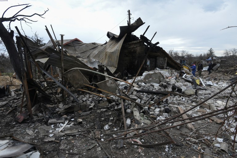 Municipal workers and a police officer inspect remains of a residential building destroyed during a Russian missile 