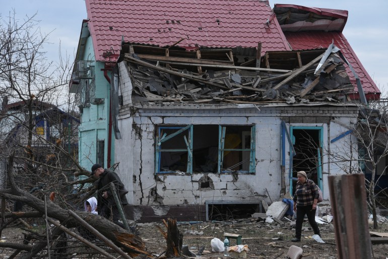 Local residents walk next to their house damaged during a Russian missile and drone strike,
