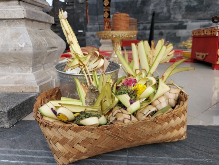 Offerings, including fruit and woven palm leaves, for the gods. They are in a basket woven from palm fronds.