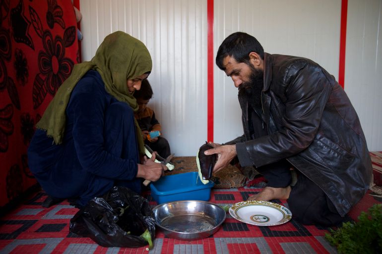 Bayan and Khaled work on the floor to peel and cop the vegetables to make maqali