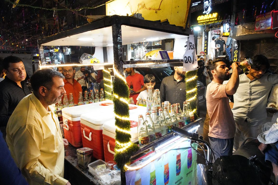 People consume soft drinks at a food stall. [Meer Faisal/Al Jazeera]