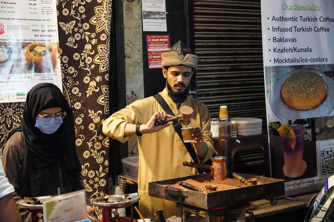 A coffee seller prepares Turkish coffee at his coffee stall. [Meer Faisal/Al Jazeera]
