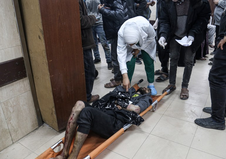 Mohamed Sukkar on a stretcher on the floor as a doctor bends over him