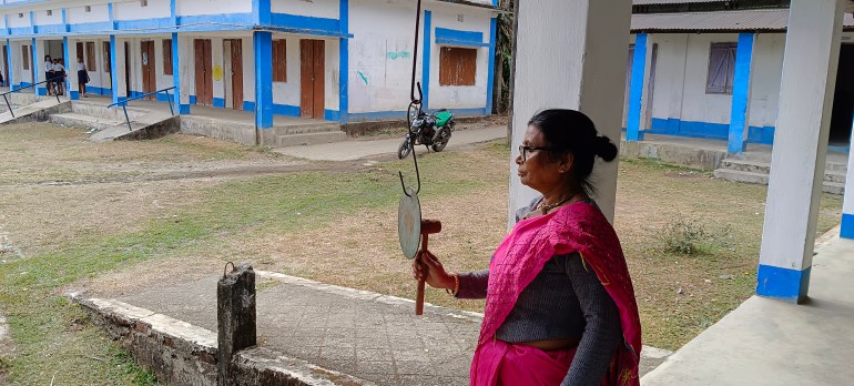 A member of the staff at Totopara's only secondary school rings the bell for lunch. The school has seen a surge in dropouts, with many teachers leaving, and the government not recruiting new ones [Gurvinder Singh/Al Jazeera]
