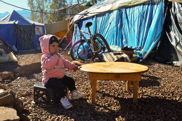 A small girl sits at a table in the camp outside Asni, near Marrakesh