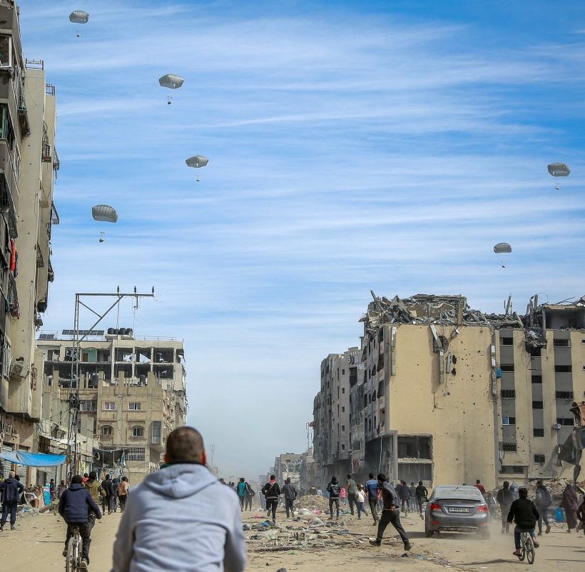 Palestinians run along a street as humanitarian aid is airdropped in Gaza City on March 1, 2024.