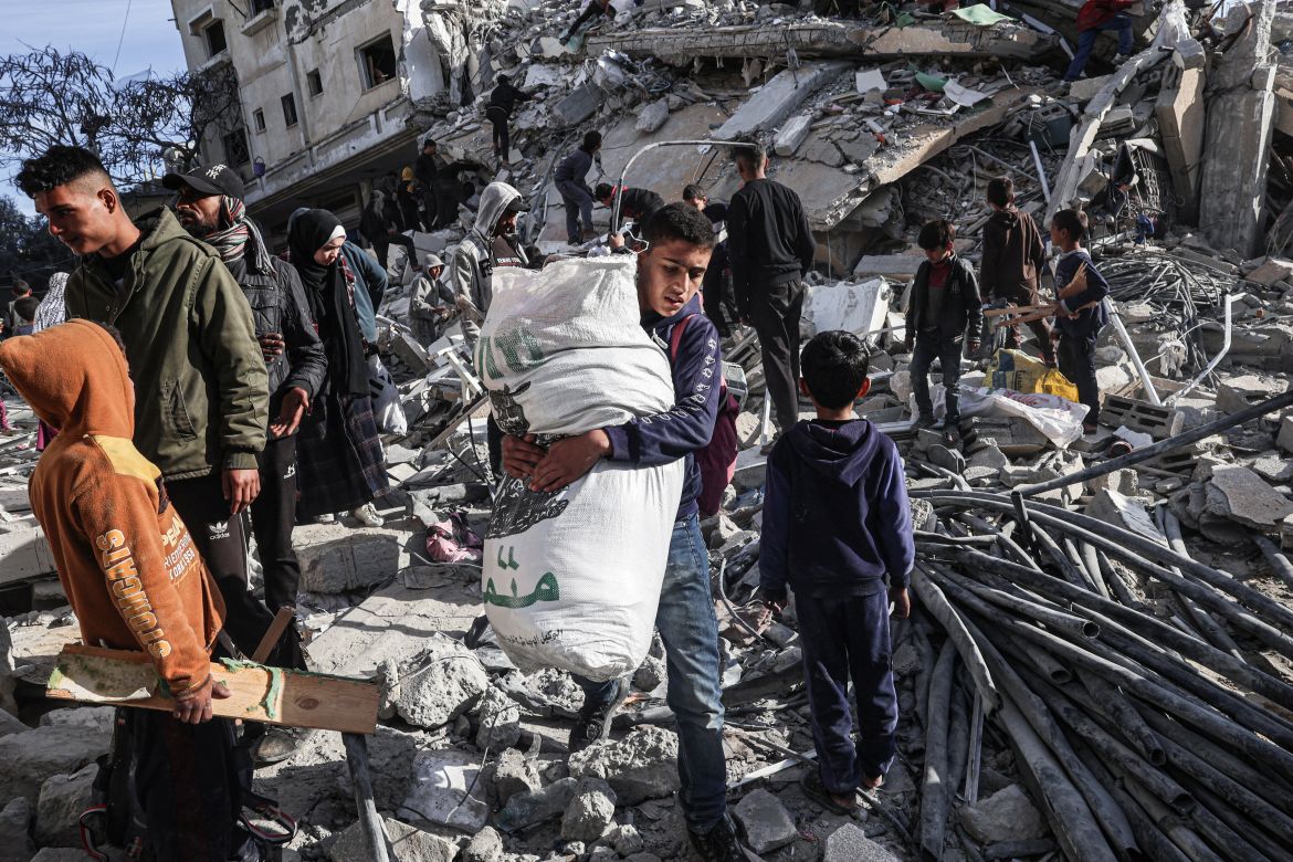 A Palestinian youth walks away with some items salvaged from the rubble of a residential building hit in an overnight Israeli air strike in Rafah in the southern Gaza Strip on March 9