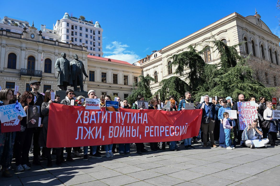 Members of the Russian diaspora in Georgia hold a banner reading as 'Enough Putin, lies, war, repressions' during a protest on the day of Russia's presidential election, in Tbilisi on March 17