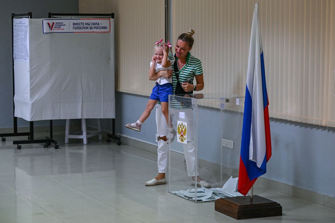 A Russian woman and a child residing in India react after casting a ballot during Russia's presidential election at a polling station set up at the Russian Centre of Science and Culture in Chennai on March 17