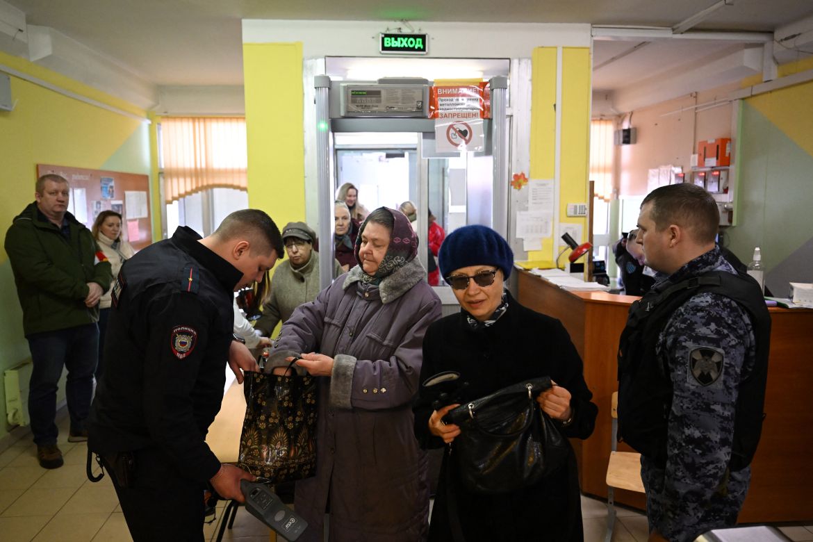 People undergoe security control as they arrive to vote in Russia's presidential election at a polling station in Moscow on March 17