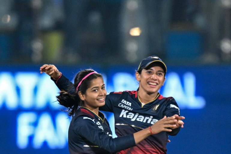 Royal Challengers Bangalore's Shreyanka Patil (L) celebrates with captain Smriti Mandhana (R) after taking the wicket of Delhi Capitals' Meg Lanning during the Women's Premier League (WPL) Twenty20 cricket final match between Royal Challengers Bangalore and Delhi Capitals at the Arun Jaitley Stadium in New Delhi on March 17, 2024. (Photo by Sajjad HUSSAIN / AFP) / -- IMAGE RESTRICTED TO EDITORIAL USE - STRICTLY NO COMMERCIAL USE -- - -- IMAGE RESTRICTED TO EDITORIAL USE - STRICTLY NO COMMERCIAL USE --