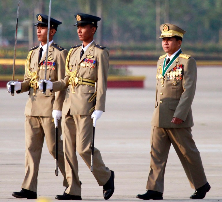 Minh Aung Hlaing at Armed Forces Day in 2012. He is accompanied by two soldiers carrying ceremonial swords. He has lots of medals on his chest.