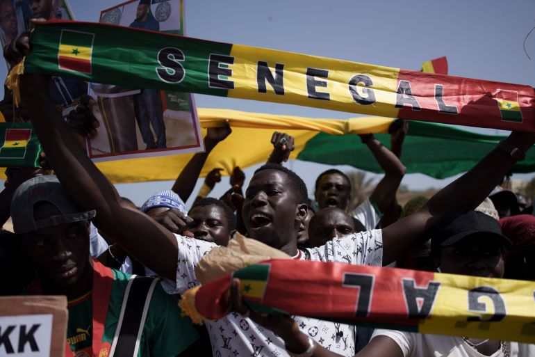 People hold a banner in the colours of Senegal's flag
