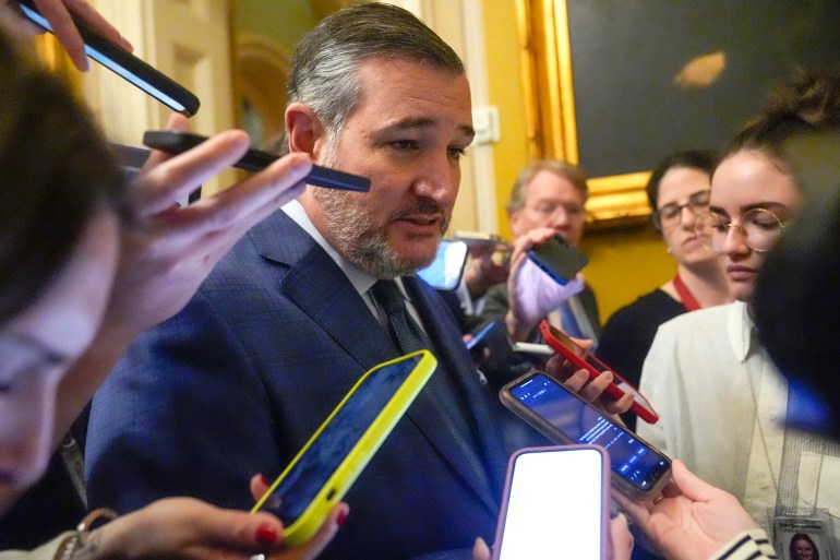 Ted Cruz walks through congress surrounded by microphones and cellphones to record.