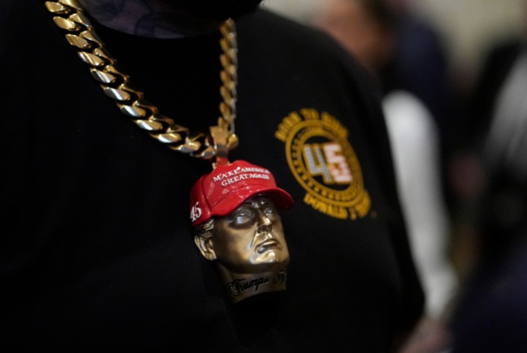 A man wears a Trump head on the end of a chain around his neck in support of the candidate.