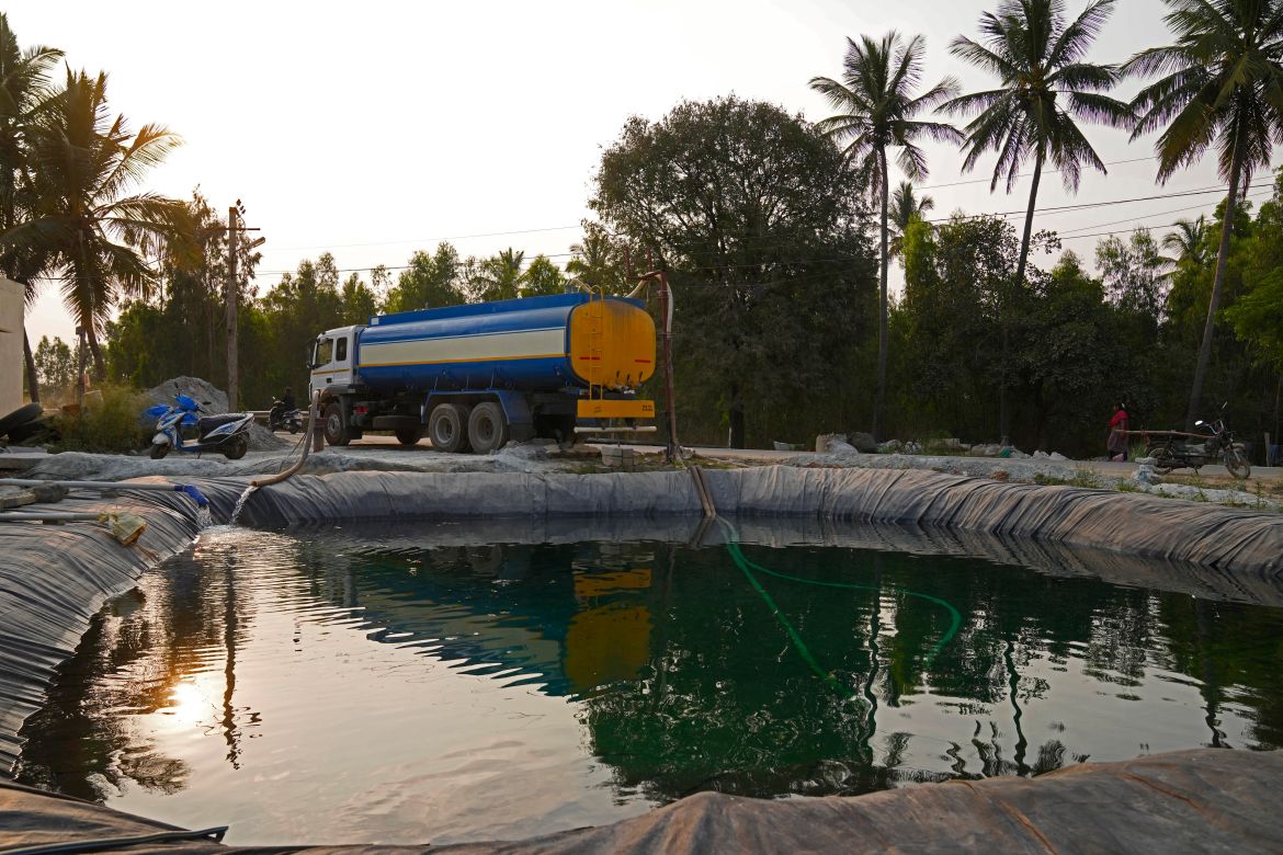 Potable water is loaded into a private water tanker from a temporary pond created to store groundwater