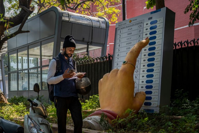 A man walks past a large model of a woman's finger pressing a button of an electronic voting machine displayed outside the office of Election Commission of India in New Delhi, India, Wednesday, March 20, 2024. From April 19 to June 1, nearly 970 million Indians - or over 10% of the world's population - will vote in the country's general elections. The mammoth electoral exercise is the biggest anywhere in the world - and will take 44 days to complete before results are announced on June 4. (AP Photo/Altaf Qadri)