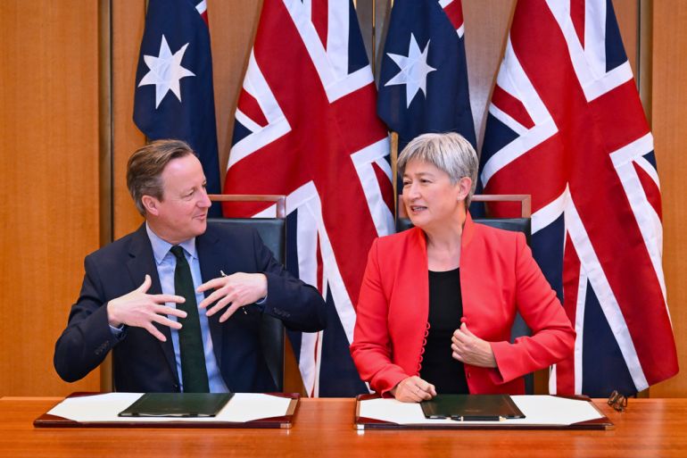 Britain's Foreign Secretary David Cameron, left, and Australian Foreign Minister Penny Wong exchange documents during a signing ceremony at Parliament House at Parliament House in Canberra