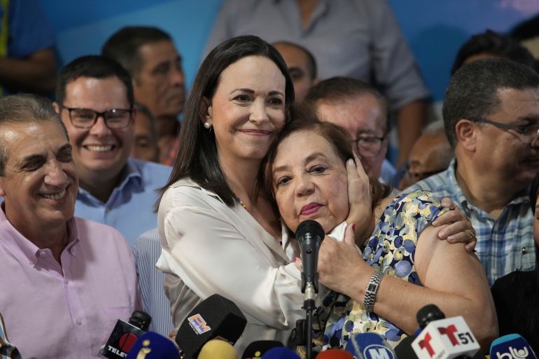 Maria Corina Machado hugs the face of Corina Yoris at a press conference.
