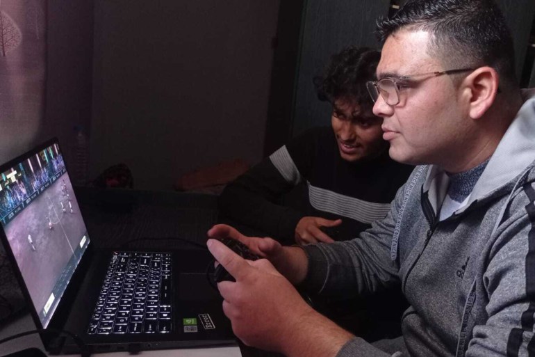 Basel AbdulJawwad and his friends play the FIFA 2023 video game in Deir al-Balah, Gaza [Abubaker Abed/Al Jazeera]