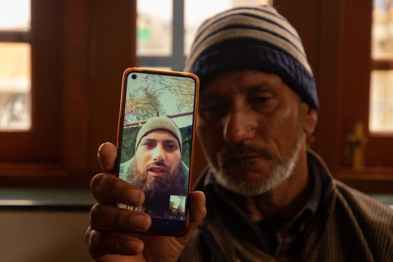 SRINAGAR, JAMMU AND KASHMIR, INDIA - 2024/02/28: A father of Azad Yousuf Kumar, holds a smart phone displaying the photos of Azad Yousuf Kumar, wearing military uniform, at Pulwama village. Two Kashmiri men Azad Yousuf Kumar 31-years old, and Zahoor Ahmad Sheikh 30-years old, who were lured to Dubai on the promise of jobs and then deceitfully dispatched to Russia by fraudulent recruitment agencies and ordered to fight as mercenaries for Russia on the border with Ukraine. A Kashmiri family learned that their son, Azad Yousuf Kumar, 31- years old, had been injured in the Russia-Ukraine conflict. The family said the 31-years old was forced to fight in the war on frontline and urged the Indian government to intervene to help them get their son back. At least a dozen Indian nationals have been duped by the agents into fighting for Russian forces in the country's war with Ukraine. According to the Indian publication 'The Hindu', one Indian national was killed in a missile strike last week. The anguished families of the trapped men have now petitioned the federal government to return them home. (Photo by Faisal Bashir/SOPA Images/LightRocket via Getty Images)