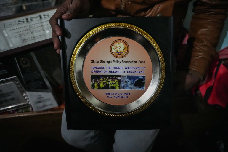 Munna Qureshi, 29, shows an award that they won for rescuing 41 trapped tunnel workers. [Md Meharban/Al Jazeera] 