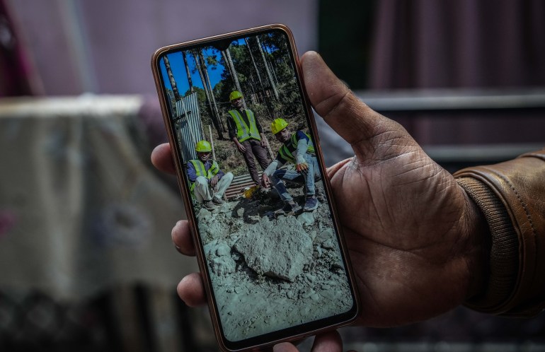 2. Munna Qureshi, 29, shows a photo on his phone showing himself, Hasan, and another rat-hole miner after tunnel rescue. [Md Meharban/Al Jazeera] 