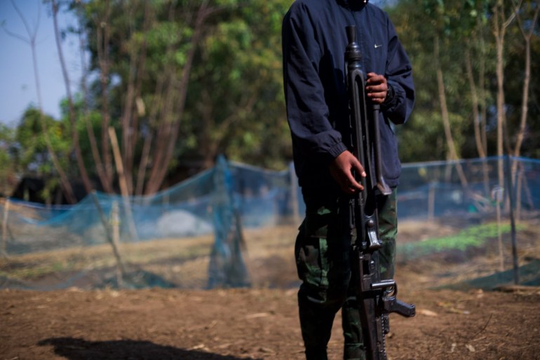 A Kayah fighter standing with a gun, His face is not visible.