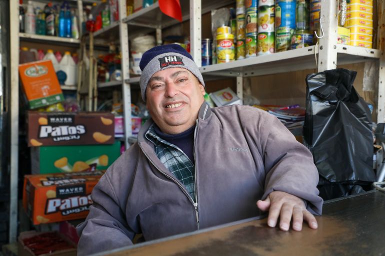 Ishaq Qafisheh smiling behind his shop counter