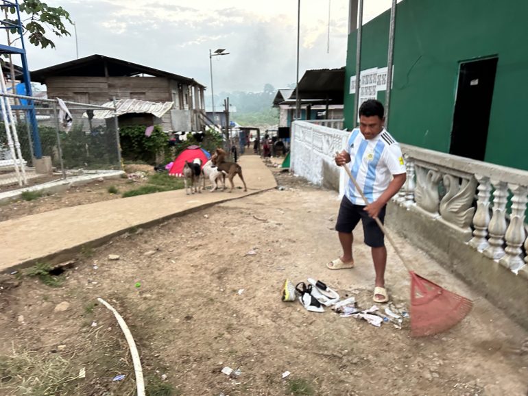 A man sweeps up trash outside in Bajo Chiquito, Panama