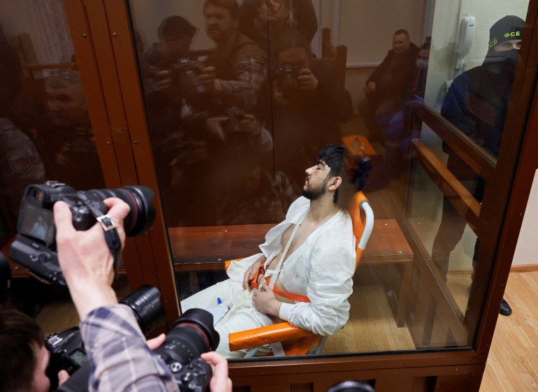 Muhammadsobir Fayzov, a suspect in the shooting attack at the Crocus City Hall concert venue, sits in a medical transport chair behind a glass wall of an enclosure for defendants before a court hearing at the Basmanny district court in Moscow, Russia March 25, 2024. REUTERS/Shamil Zhumatov