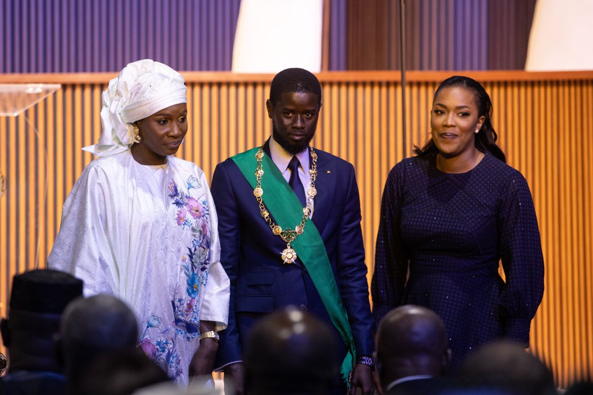 Newly sworn in Senegalese President Bassirou Diomaye Faye (C), stands with his wives Marie, (R) and Absa (L) during his inauguration ceremony at the Abdou Diouf International Convention Centre in Diamniadio, Senegal
