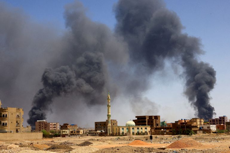 A man walks while smoke rises above buildings after aerial bombardment, during clashes between the paramilitary Rapid Support Forces and the army in Khartoum North, Sudan, May 1, 2023
