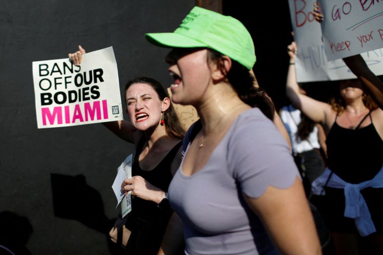 Women protest for abortion access, with one holding up a sign that reads, "Ban off our bodies Miami."