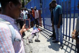 People look at the body of a man as rival gangs vie for control in Port-au-Prince, Haiti, on April 1, 2024 [Reuters]