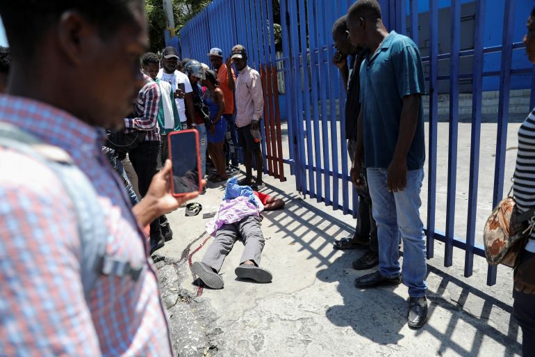 People look at the body of a dead man as rival gangs are vying for control of turf in Port-au-Prince, Haiti, April 1, 2024