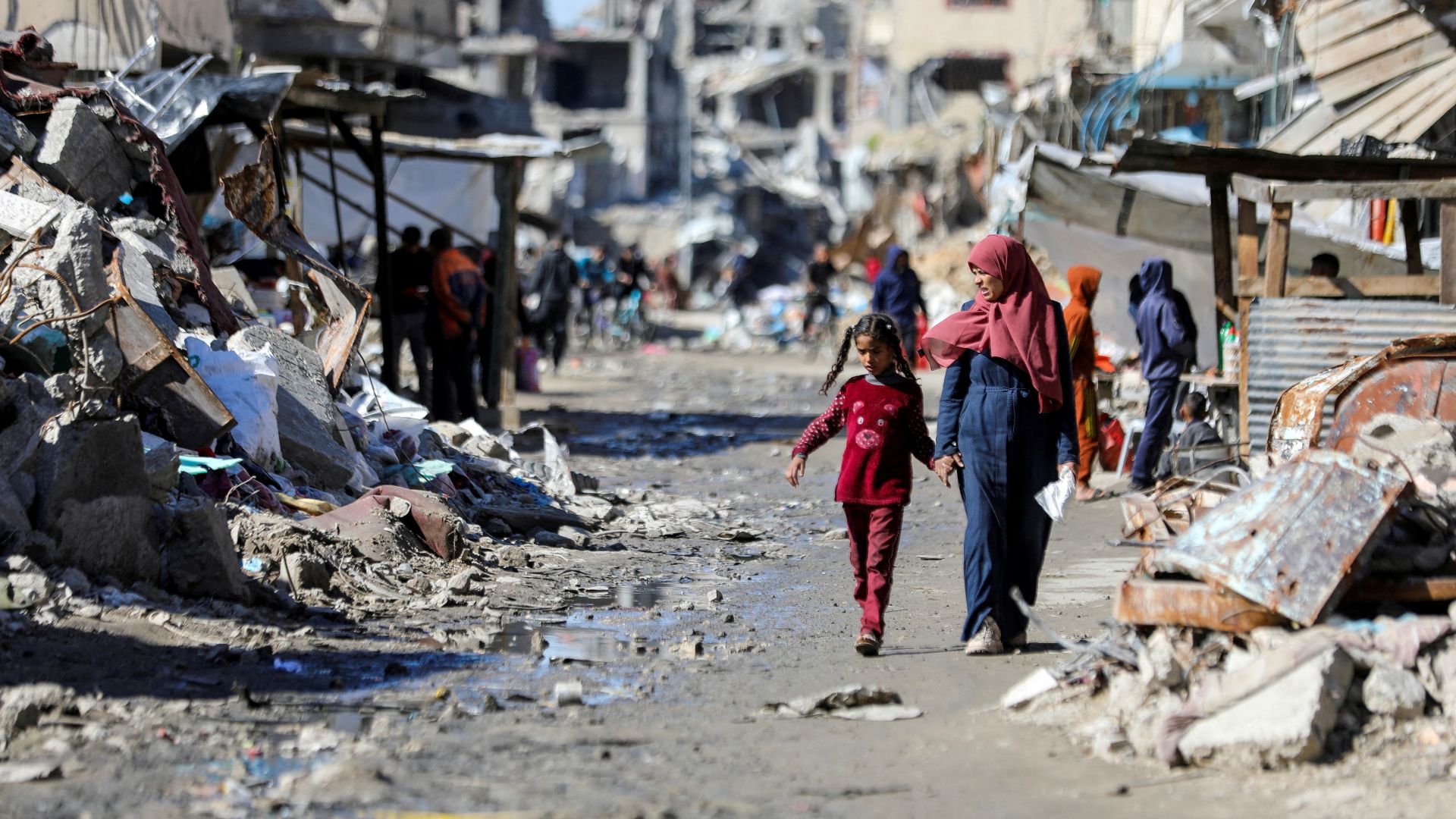 Palestinians walk past destruction in Gaza