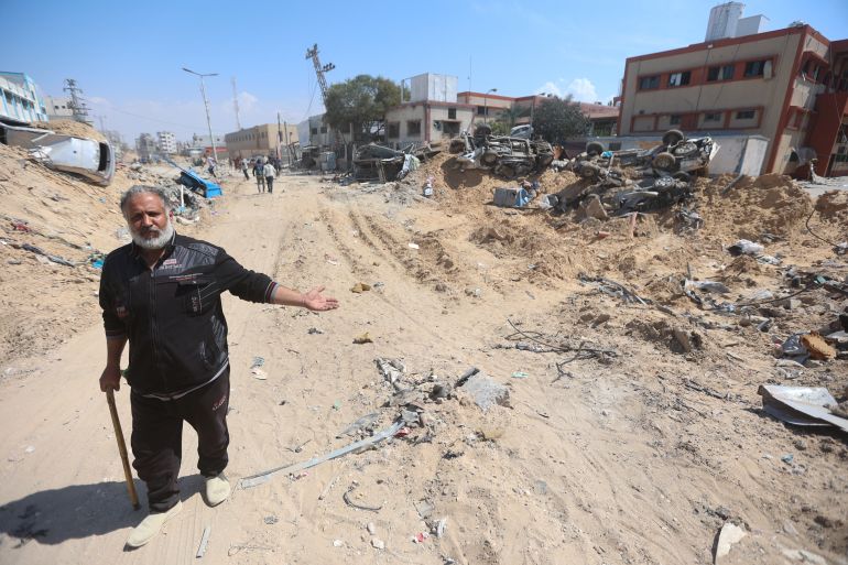 A man gestures as Palestinians inspect destroyed residential buildings and vehicles, after the Israeli military withdrew most of its ground troops from the southern Gaza Strip
