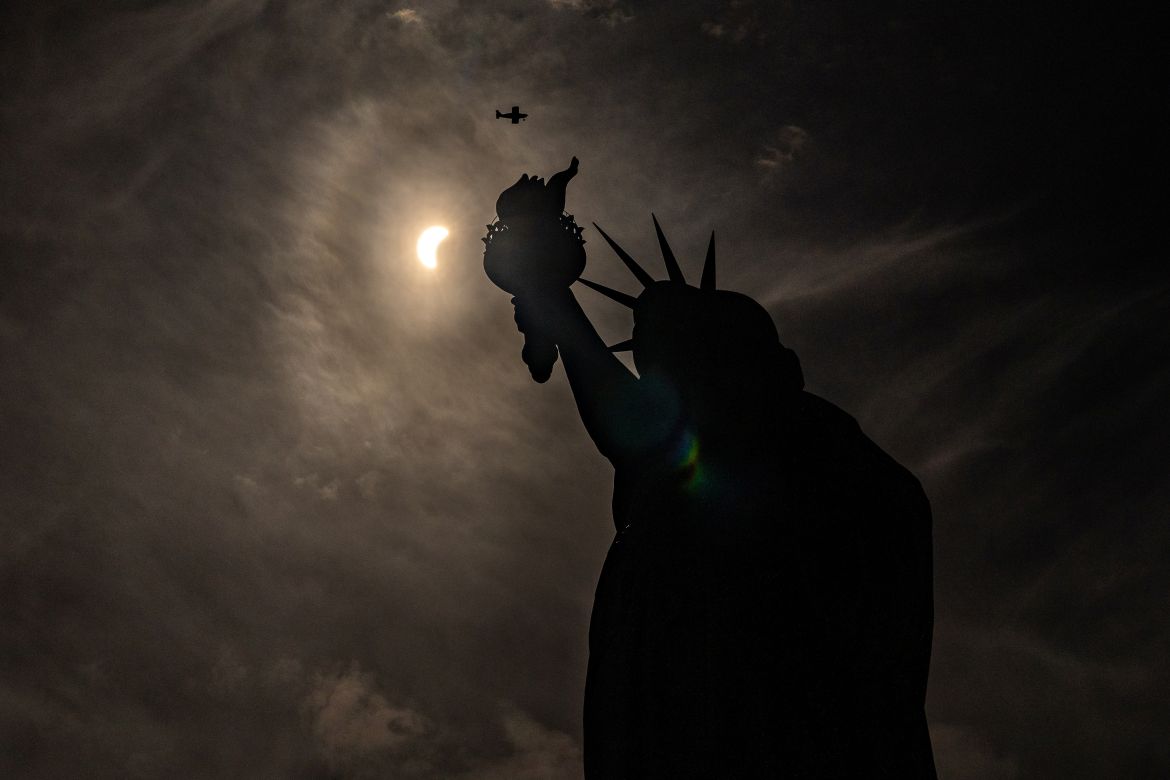 The Statue of Liberty is seen in shadow as the eclipse unfolds