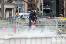 A police officer uses a fire extinguisher after responding to a person covered in flames outside the courthouse where former US President Donald Trump facing criminal trial. [Brendan McDermid/Reuters]