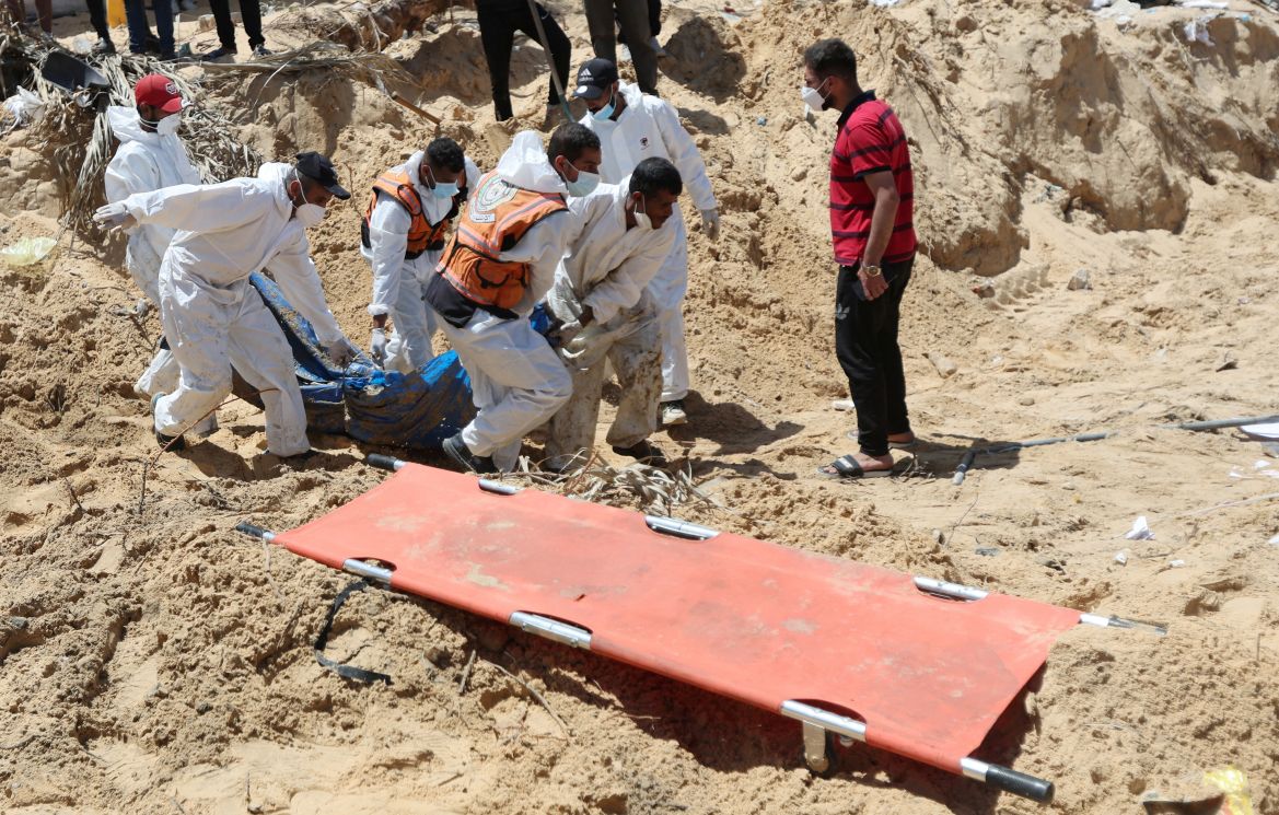 People work to move into a cemetery bodies of Palestinians killed during Israel's military offensive and buried at Nasser hospital