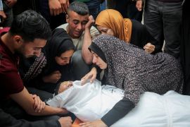 Mourners react as the look at the body of a Palestinian killed in an Israeli strike during a funeral in Rafah [Hatem Khaled/Reuters]