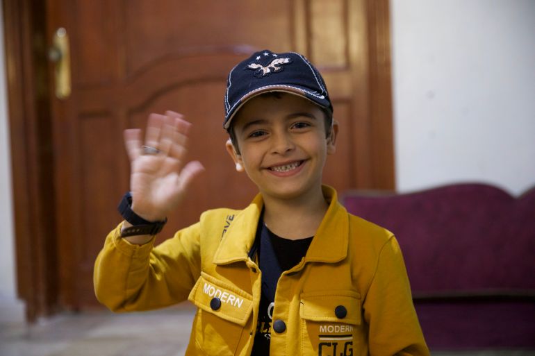 Aslan smiles and waves in his home in Idlib, Syria