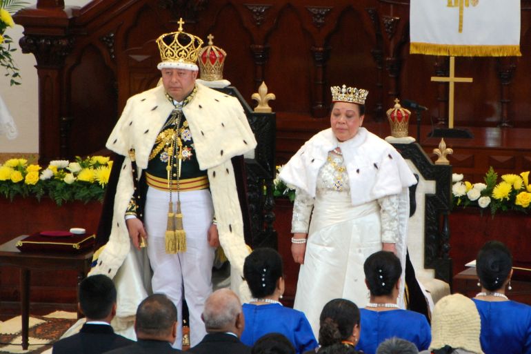 Tonga's king at his coronation. He is with his queen. They are wearing ceremonial robes and crowns