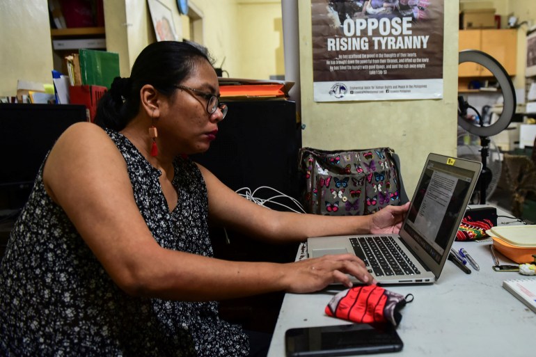 Cristina Palabay, head of local human rights group Karapatan, She is at her desk on her computer.